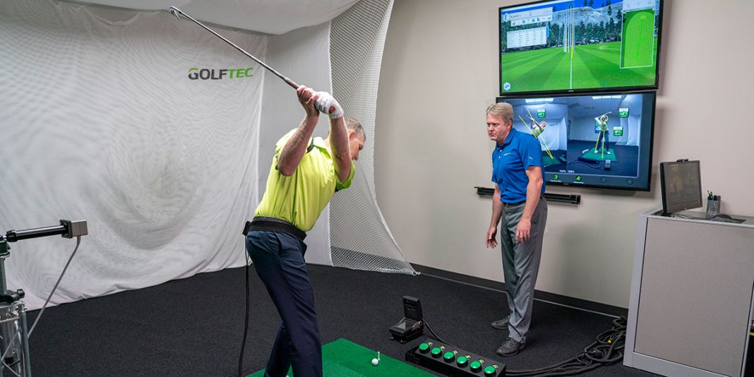 A GOLFTEC instructor analyzes his student's swing.