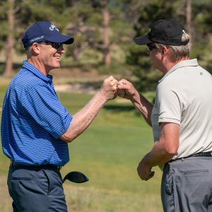 Two men fist bump on the golf course.