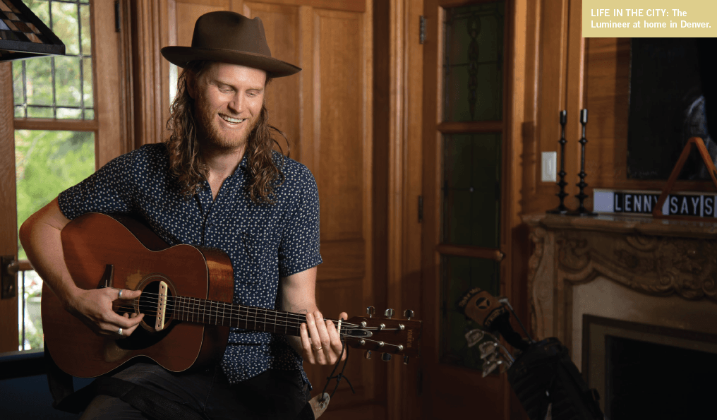 Wesley with a grin and his guitar in his home in Denver.