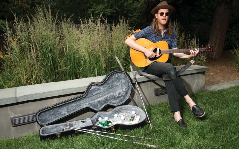 Wesley Schultz of the Lumineers poses with his guitar in the backyard of his Denver home.