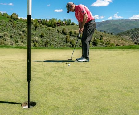 A golfer sets up to a putt on the green.