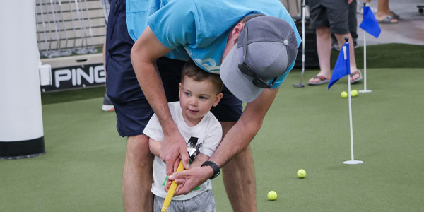 A child putts with his father at PGA TOUR Superstore