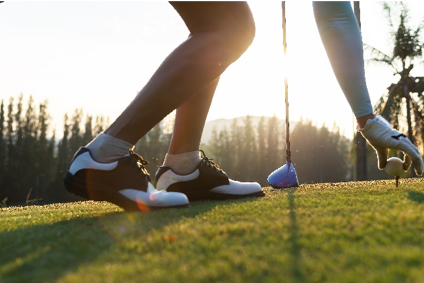 A golfer placing a ball on a tee.