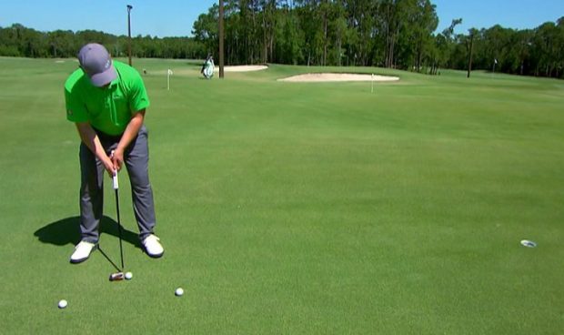 A golfer practices his putting stroke.