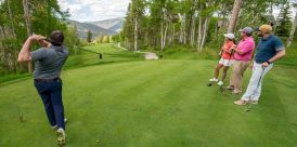 A golfer tees off in front of his buddies