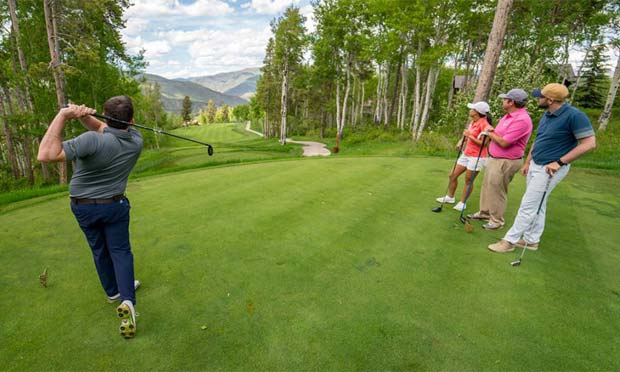 A golfer tees off in front of his buddies