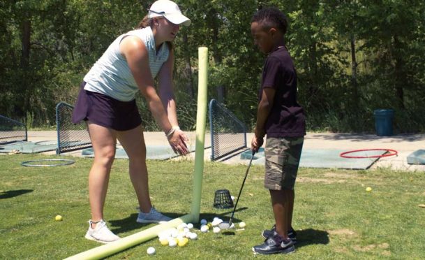 Maggie Hartman teaches a young student at CommonGround golf course in Aurora, Colorado