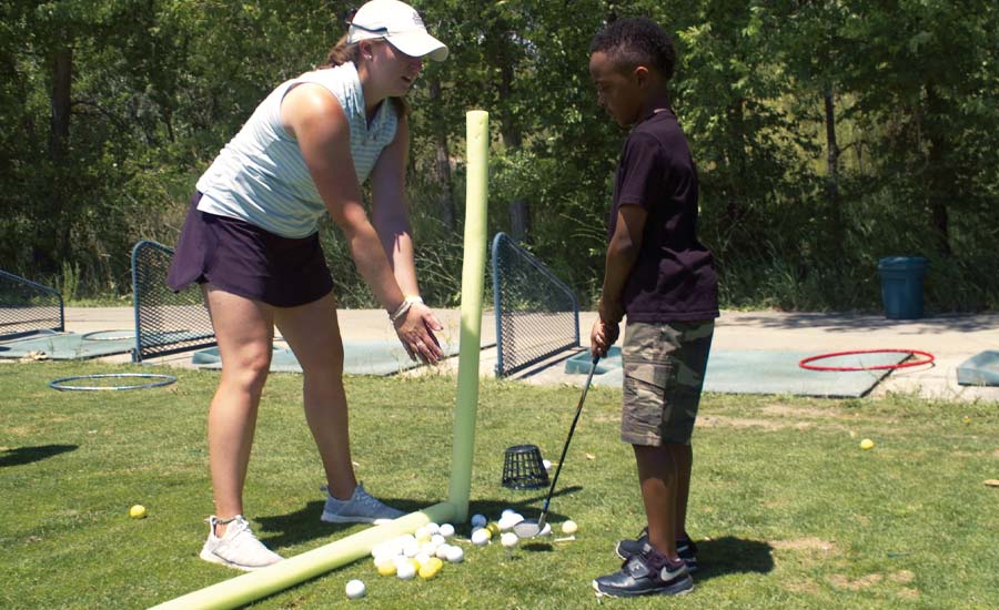 Maggie Hartman teaches a young student at CommonGround golf course in Aurora, Colorado